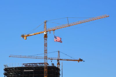 A contruction crane, with a American flag flying below, on a construction site in San Diego, California.