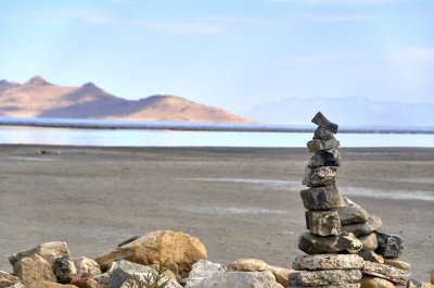 A rock cairn with the receding shoreline of the Great Salt Lake in the intentionally out of focus background, at the Great Salt Lake State Park in Utah.